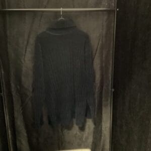 A black sweater hanging in the corner of a room.