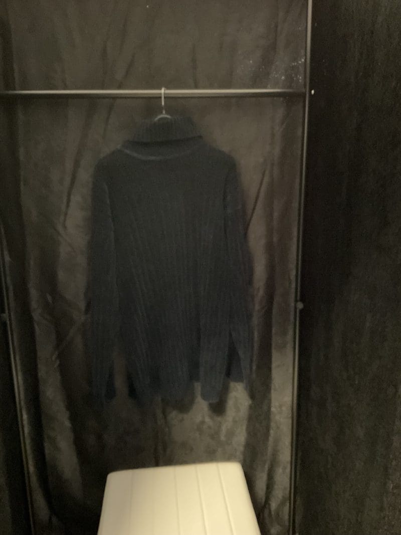 A black sweater hanging in the corner of a room.