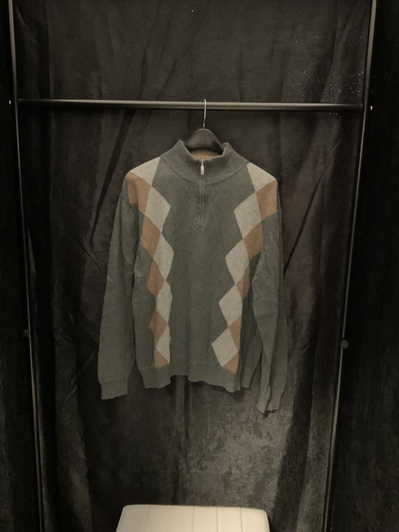 A sweater hanging on a rack in a room.