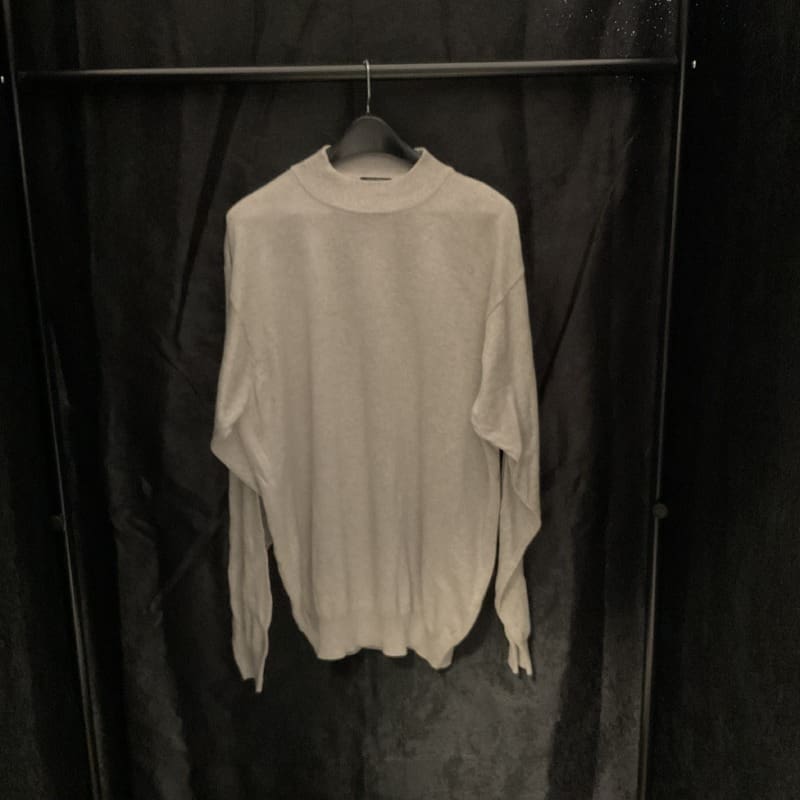 A white sweater hanging on a black curtain.