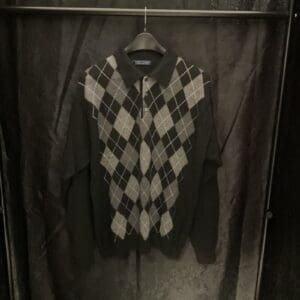 A black and white argyle sweater hanging on a rack.