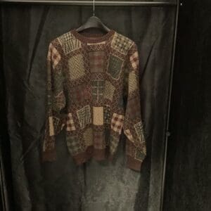 A sweater hanging on the wall in a closet.