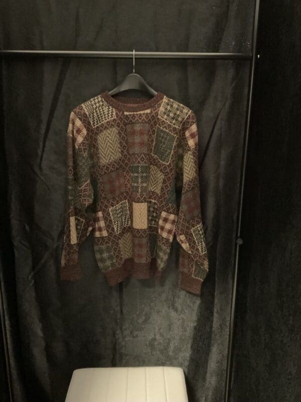 A sweater hanging on the wall in a closet.