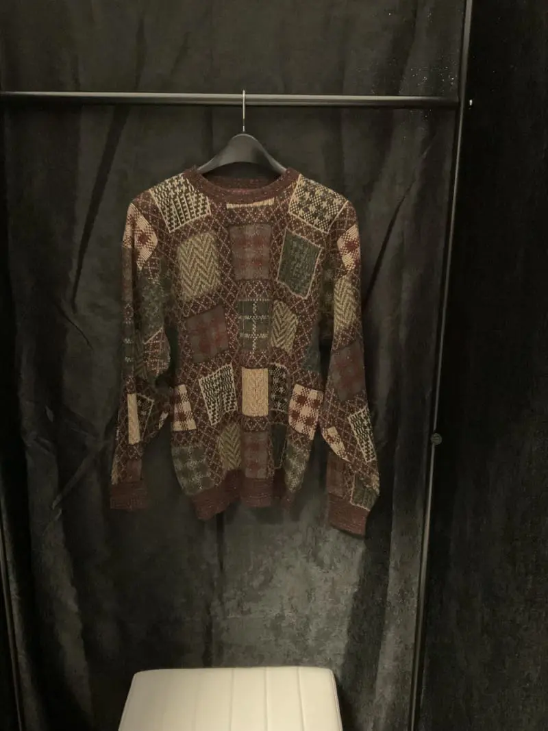 A sweater hanging on the wall in a closet.