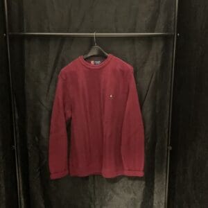 A red sweater hanging on a black wall.