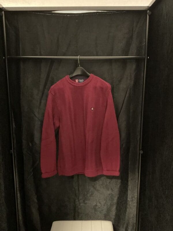 A red sweater hanging on a black wall.