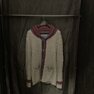 A sweater hanging on the wall in a closet.