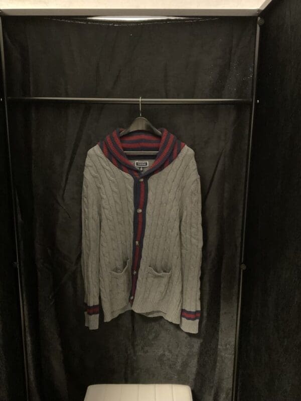 A sweater hanging on the wall in a closet.