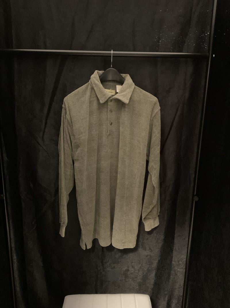 A shirt hanging on the wall in front of a curtain.