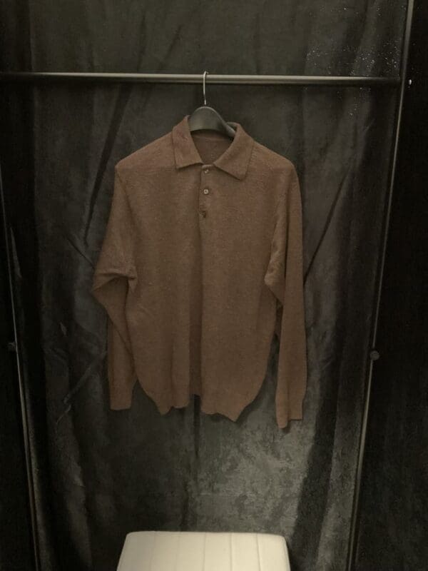 A brown shirt hanging on a metal rack.