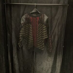 A hanging clothes rack with a red and black striped shirt on it.