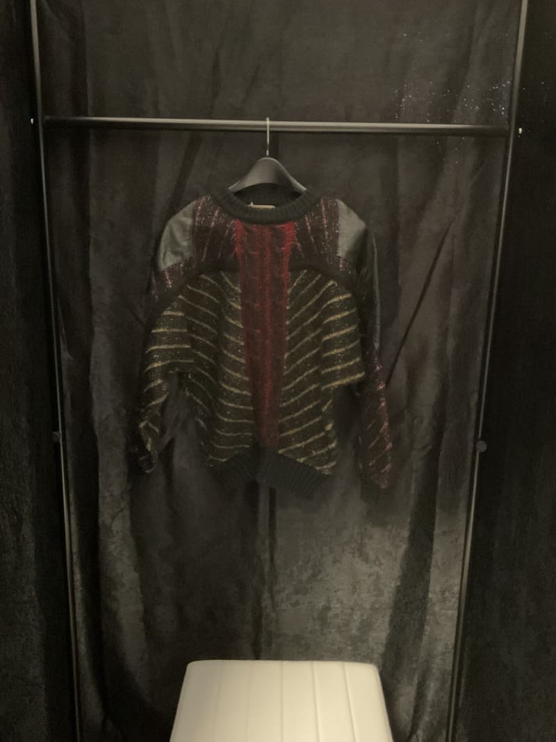 A hanging clothes rack with a red and black striped shirt on it.