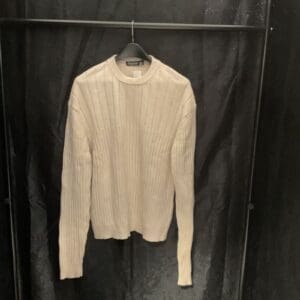 A white sweater hanging on a black wall.