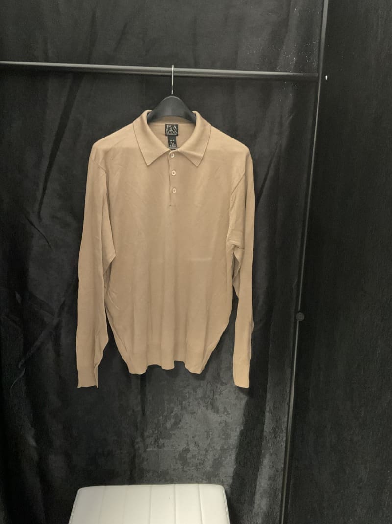 A tan shirt hanging on the wall