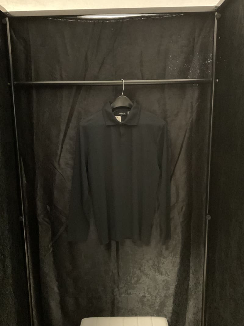 A black shirt hanging in the corner of a room.