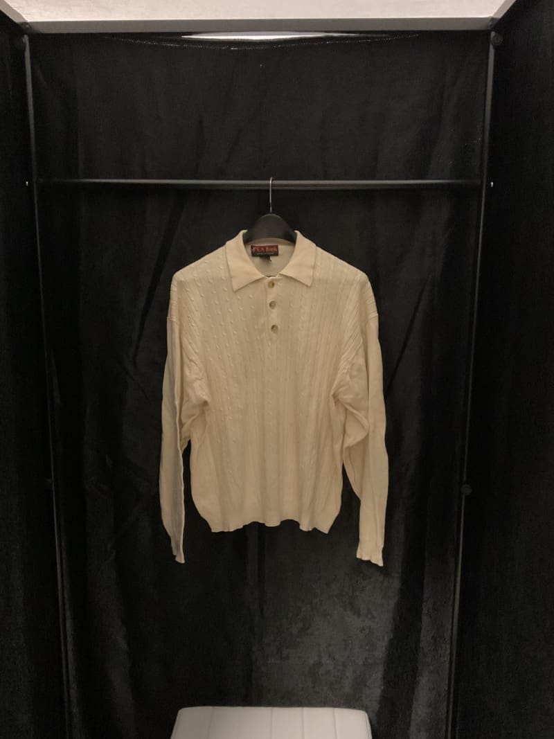 A white shirt hanging on a black wall.