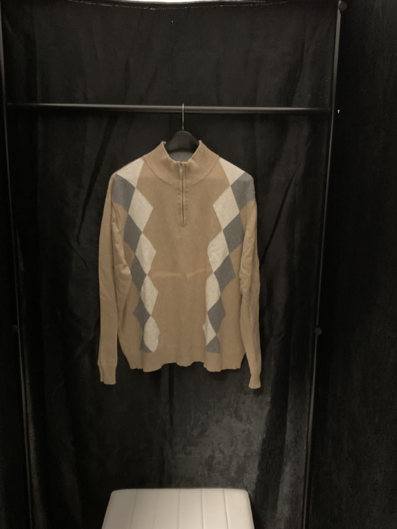 A sweater hanging on the wall in a closet.