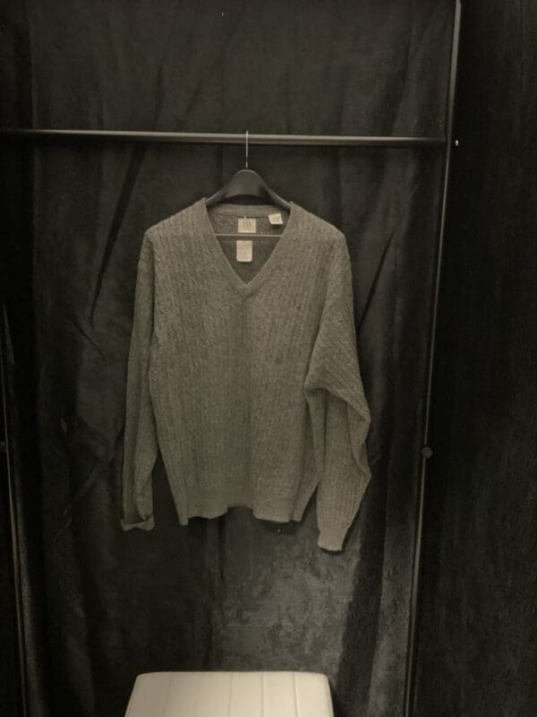 A sweater hanging on the wall in a closet.