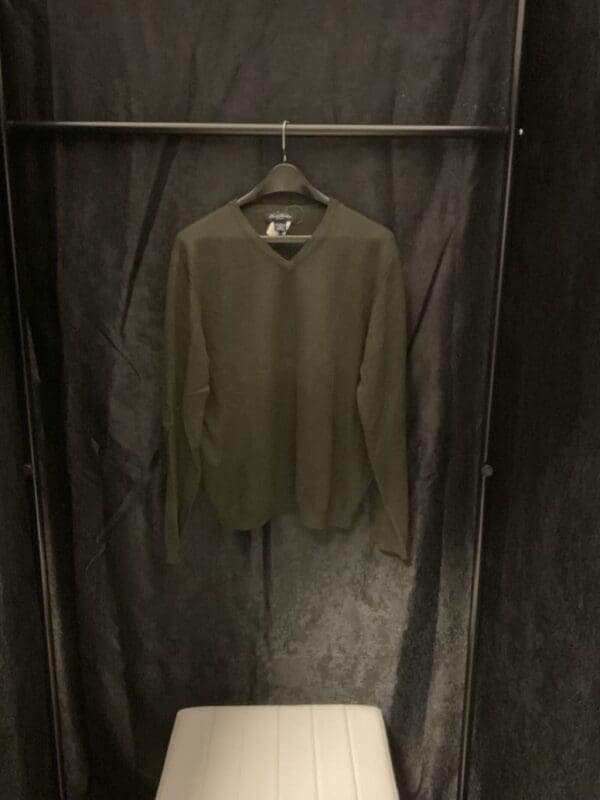 A green shirt hanging in a closet with no clothes.