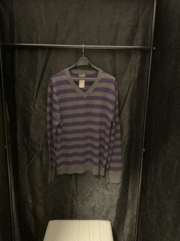 A purple and gray striped sweater hanging on a rack.