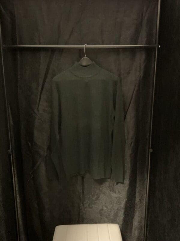 A dark room with a hanging shirt on the rack