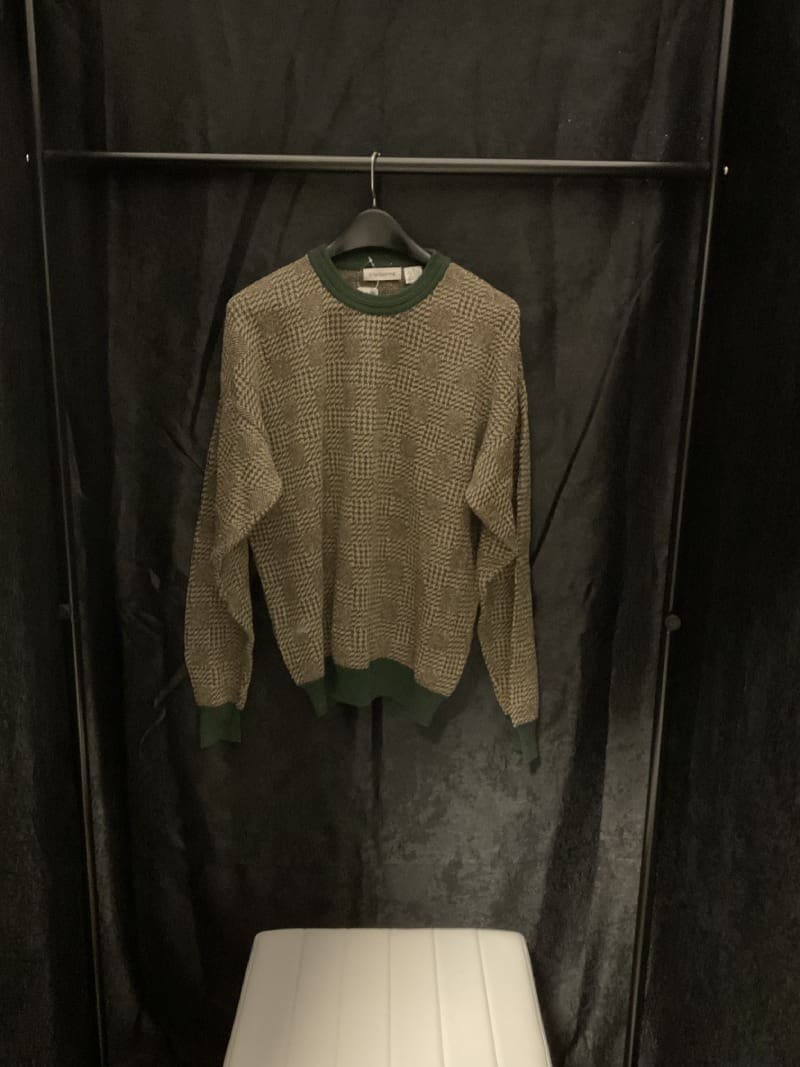 A sweater hanging on the wall in a closet.