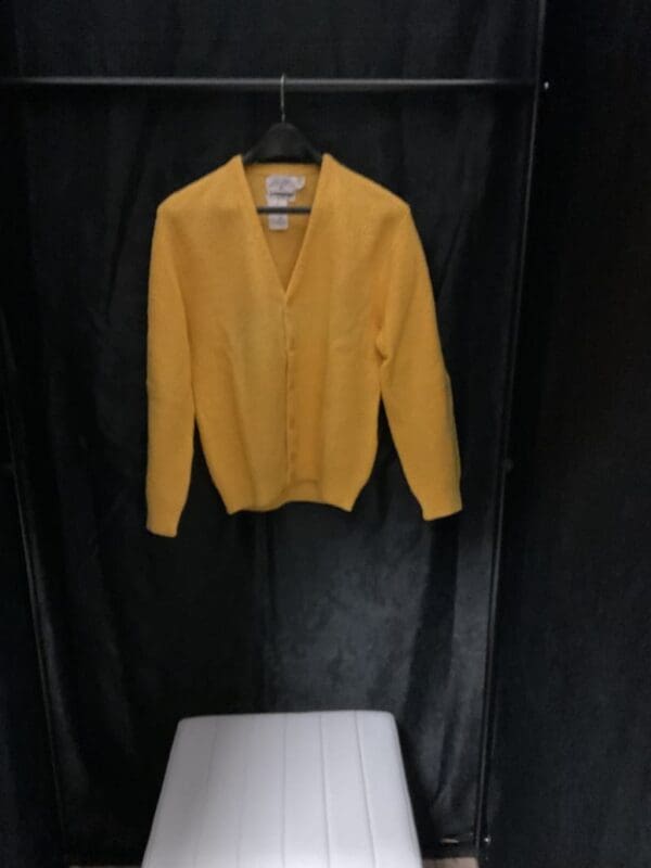 A yellow sweater hanging on the wall