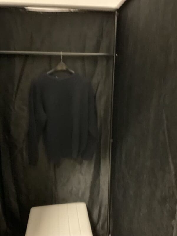 A black shirt hanging on the wall in a bathroom.