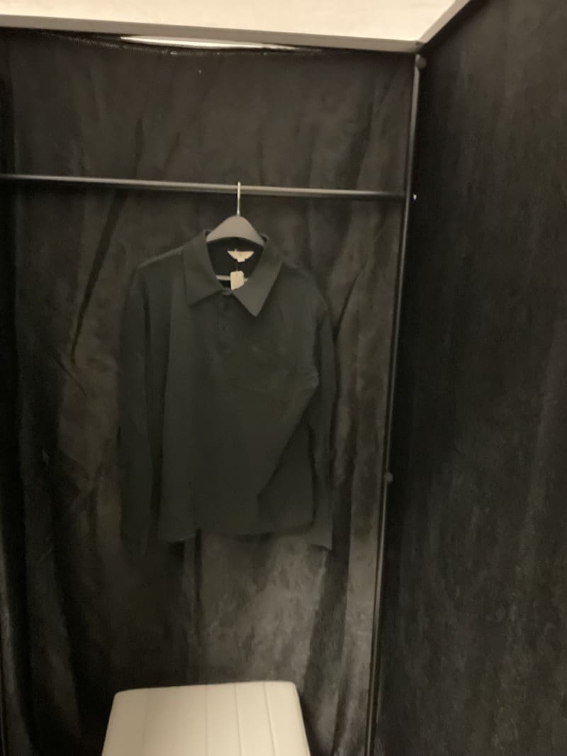 A black shirt hanging on a clothes rack.