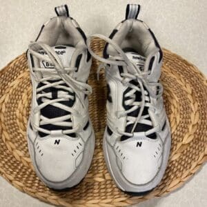 A pair of white and black sneakers sitting on top of a straw mat.