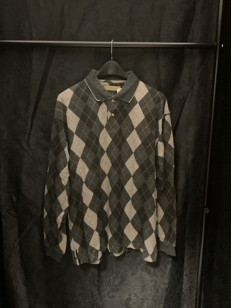 A black and white argyle shirt hanging on a rack.