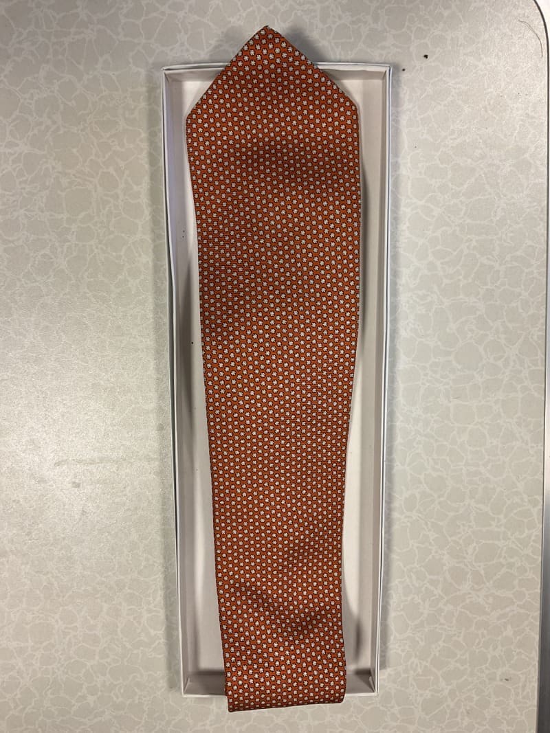 A brown tie in the box on top of a table.