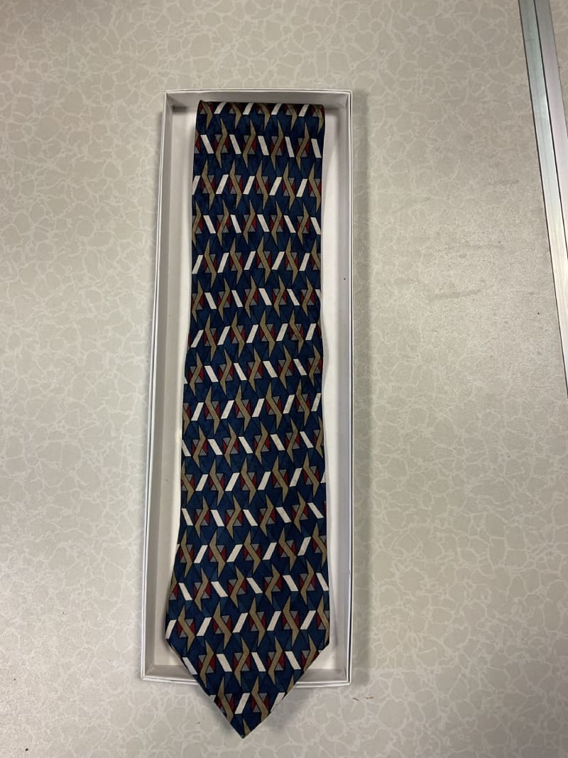 A tie that is in its box on the floor.