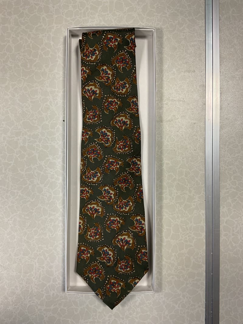 A tie hanging on the wall in front of a door.