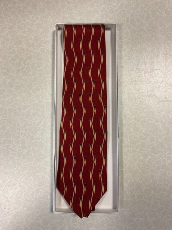 A red tie with white stripes hanging on the wall.