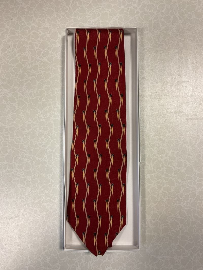 A red tie with white stripes hanging on the wall.