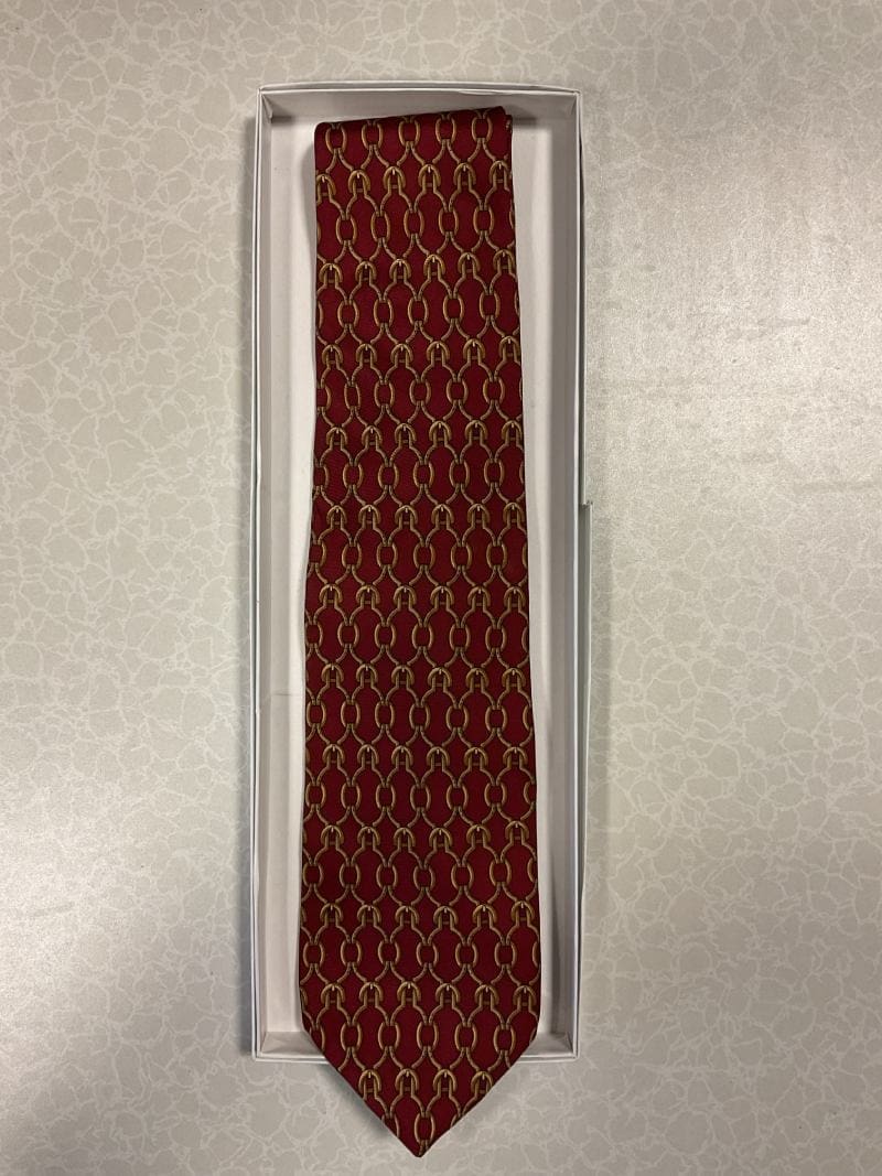 A red tie with gold thread in a box.