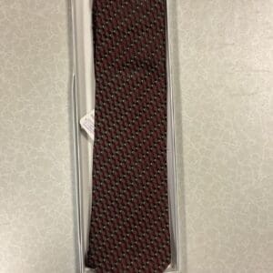 A tie that is in its box on the floor.