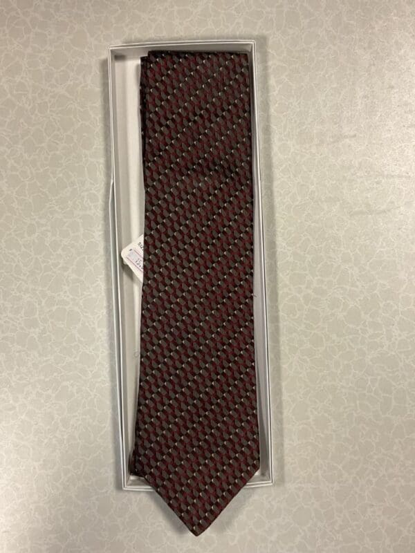 A tie that is in its box on the floor.