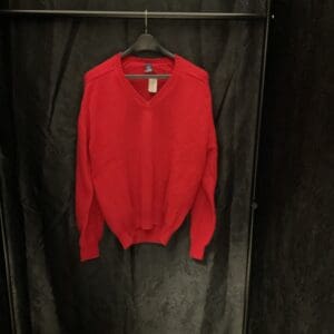 A red sweater hanging on a black wall.