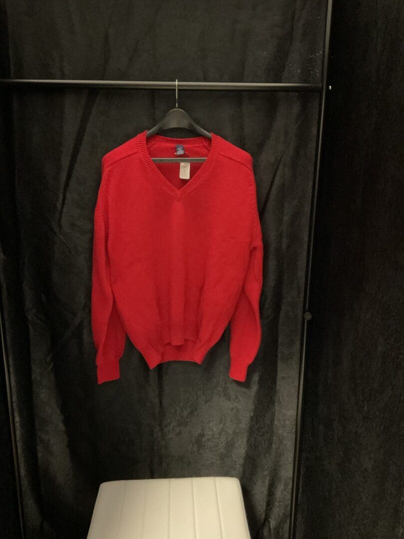 A red sweater hanging on a black wall.