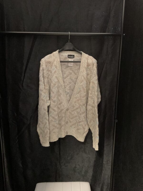 A white sweater hanging on a black wall.