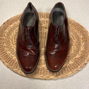 A pair of brown shoes sitting on top of a straw mat.