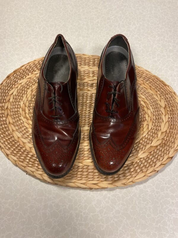 A pair of brown shoes sitting on top of a straw mat.