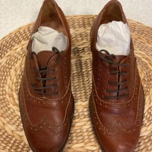 A pair of brown shoes sitting on top of a wicker basket.