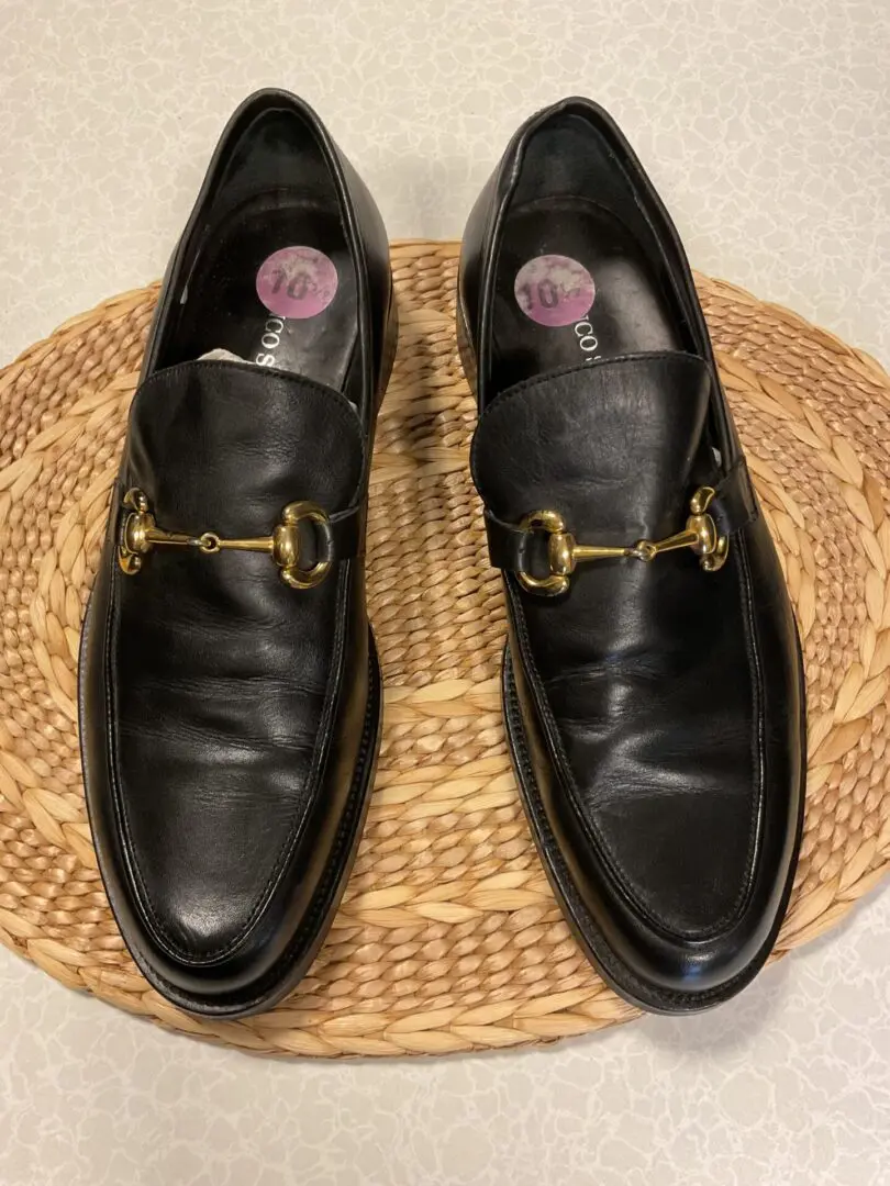 A pair of black shoes sitting on top of a wicker mat.