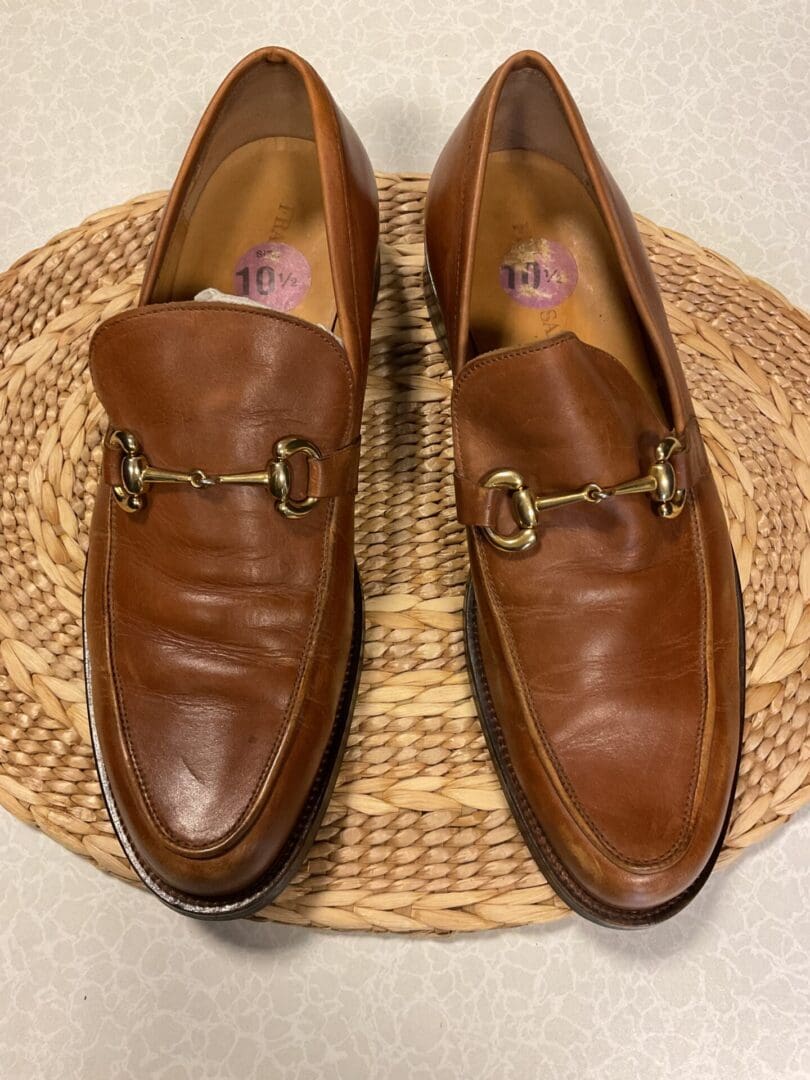 A pair of brown shoes sitting on top of a wicker mat.