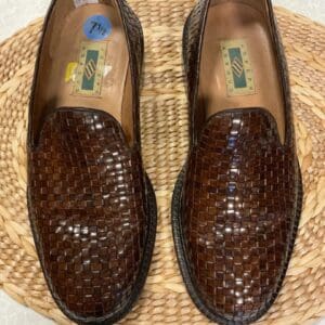 A pair of brown shoes sitting on top of a wicker mat.