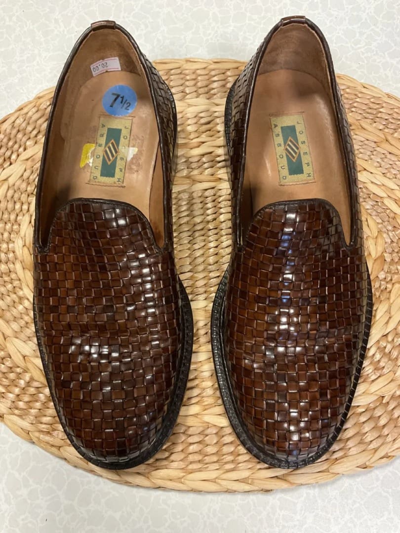 A pair of brown shoes sitting on top of a wicker mat.