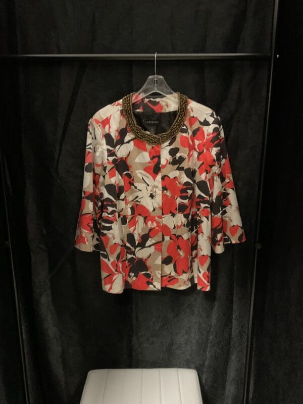 A black and red floral shirt hanging on a wall.